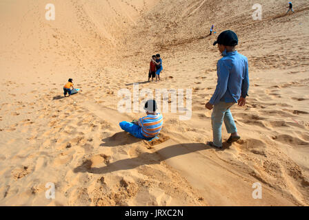 Junge Menschen haben sich funthrowing durch die Wüste Sand an den weißen Sanddünen, Mui Ne, Vietnam. Stockfoto