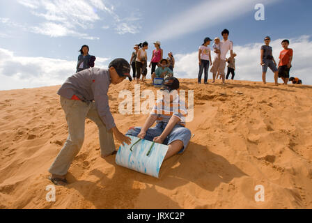 Junge Menschen haben sich funthrowing durch die Wüste Sand an den weißen Sanddünen, Mui Ne, Vietnam. Stockfoto