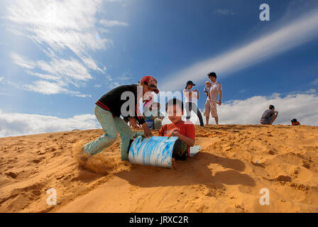 Junge Menschen haben sich funthrowing durch die Wüste Sand an den weißen Sanddünen, Mui Ne, Vietnam. Stockfoto