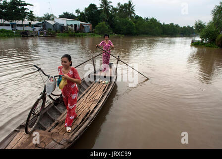 Frau mit Fahrrad übergesetzt von Sampan auf einem Nebenfluss des Flusses Mekong Delta region, Mekong Delta, Vietnam. Frau paddlling Frau in Stockfoto