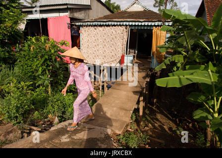 Ein Mädchen aus ihrem Haus in Can Tho am Hua Fluss im Mekong Delta in Vietnam mit Kleidung aufhängen Stockfoto