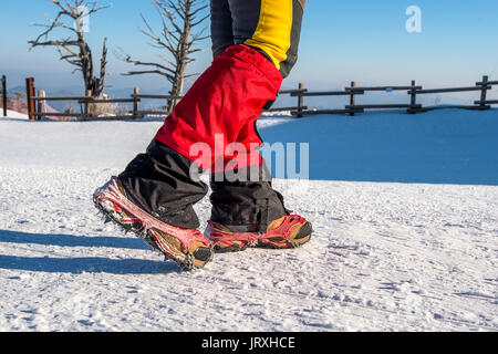 Blick auf das Gehen auf Schnee mit Schneeschuhen und Schuh Spikes im Winter. Stockfoto