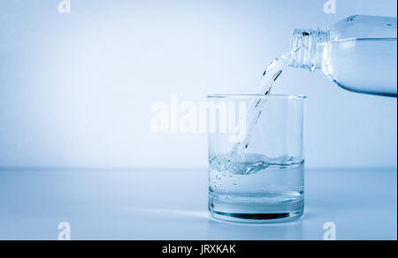 Das Gießen von Wasser aus Flasche in Glas Stockfoto