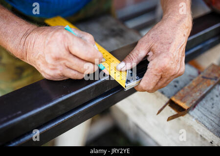 Mann messen aus Metall bar in der Werkstatt. Stockfoto