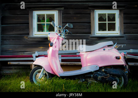 Rosa Roller steht in der Nähe von Altes holz Gebäude geparkt Stockfoto