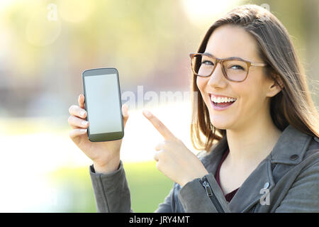 Glückliche Frau tragen Brillen zeigt einen leeren Bildschirm "Telefon" auf der Straße Stockfoto