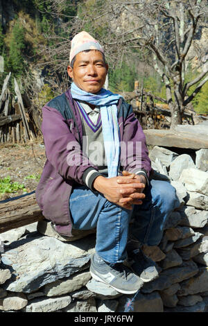 Freundliche nepalesische Mann sitzt auf einem trockenen Steinmauer, Annapurna Circuit. Stockfoto