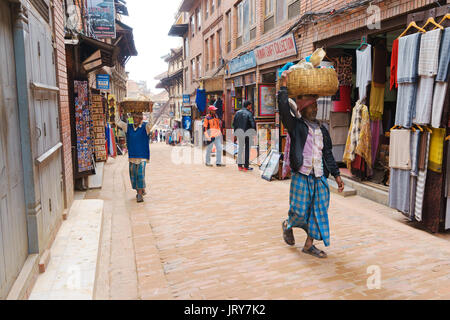 Männer und Merchandise in Körben auf dem Kopf statt. Bhaktapur, Nepal. Stockfoto