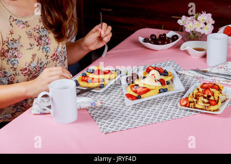 Junge hübsche Frau Frühstück mit Waffeln mit Tisch im Wohnzimmer. Toning. Stockfoto