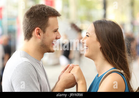 Glückliches Paar in der Liebe schauen, miteinander lachen und Hand in Hand auf der Straße Stockfoto