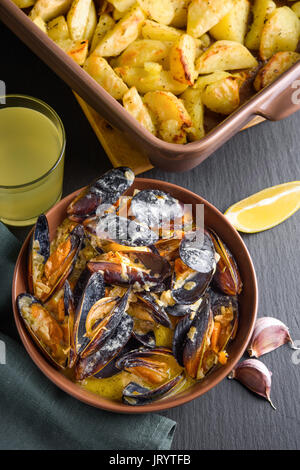 Schalentiere Muscheln in der Schüssel serviert mit gebackenen Kartoffel mit Sellerie, Knoblauch und Zitrone. Hohe Blickwinkel anzeigen Stockfoto