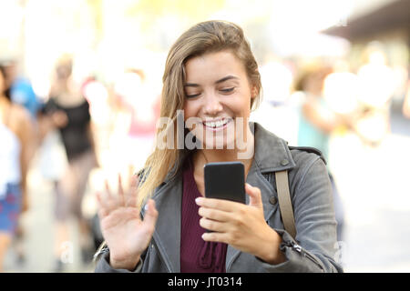 Vorderansicht Portrait Of Happy Teen Begrüßung Videocall auf der Straße Stockfoto