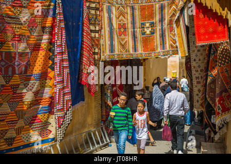 Das Leben auf der Straße. Teppiche mit traditionellen Mustern zum Verkauf zu einem souq, Markt, Basar. Souk Medina von Fes, Fes el Bali. Marokko, Maghreb Nordafrika Stockfoto