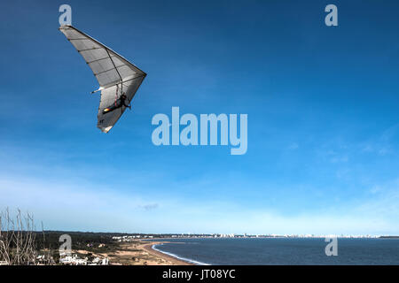 Punta del Este, die Atlantikküste, Uruguay - August 2, 2017: Hängegleiter fliegt über die Punta Ballena Cape, vor dem Hintergrund der Resort City Stockfoto