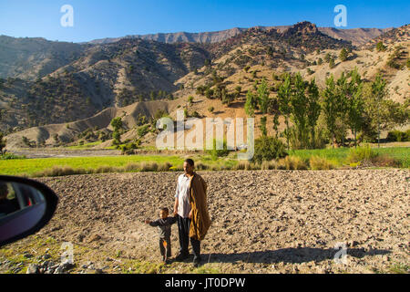 Mann und der Junge auf dem Feld beobachten ein Fahrzeug übergeben. Hohen Atlas. Marokko, Maghreb Nordafrika Stockfoto