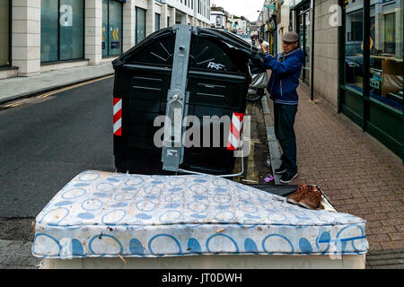 Ein lokaler Mann sieht ein Bett, die an der Seite von einem Abfallbehälter, Brighton, Sussex, UK Links Wurde Stockfoto
