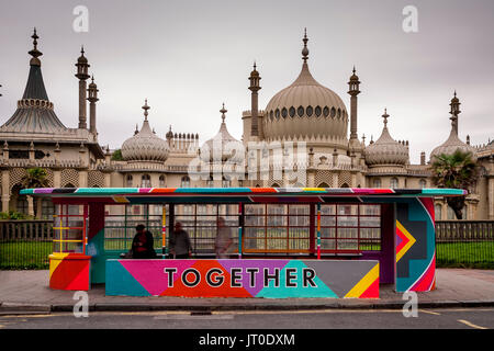 Die Menschen warten auf einen Bus in einem bunt bemalten Bus Shelter, Brighton, Sussex, UK Stockfoto