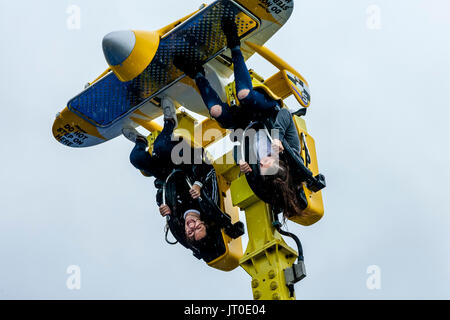 Zwei junge Frauen mit einer Messe Fahrt im Regen am Pier von Brighton, Brighton, East Sussex, Großbritannien Stockfoto