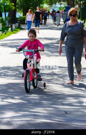 Dabushka und Enkelin fahren mit dem Fahrrad in der City Park. 28. Mai 2017. Stockfoto