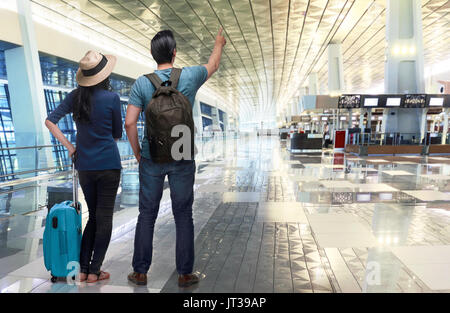 Asiatische paar Traveler zeigt mit der Hand auf dem Flughafen aufgeregt Stockfoto