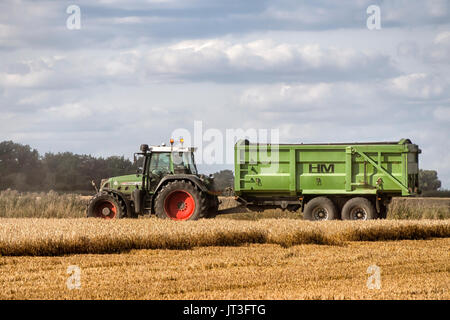 ROCHFORD, ESSEX, Großbritannien - 06. AUGUST 2017: Traktor und Anhänger warten darauf, während der Ernte zum Start des geernteten Getreides aufgerufen zu werden. Stockfoto