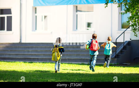 Kinder mit Rucksäcken im Park in der Nähe der Schule läuft. Schülerinnen und Schüler mit Bücher und Rucksäcke im Freien Stockfoto