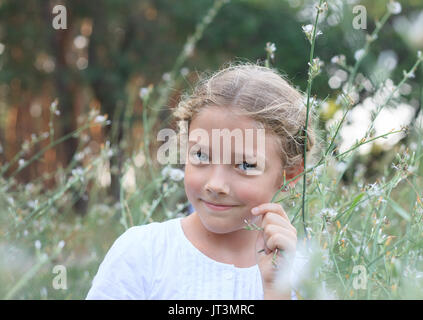 Porträt eines niedlichen kleinen Mädchen auf der Natur in den Blumen beim Gehen. Stockfoto