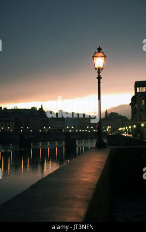 Nacht in Florenz. Glühende Vintage Straßenlaterne auf Hintergrund mit Fluss Arno Stockfoto