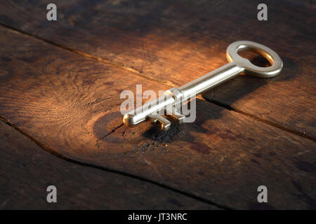 Nahaufnahme von Vintage goldene Schlüssel liegen auf alten Holz- Oberfläche mit Lichtstrahl Stockfoto