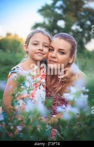 Ortrait von Mutter und Tochter von der Natur in den Blumen an einem schönen Sommertag. Stockfoto