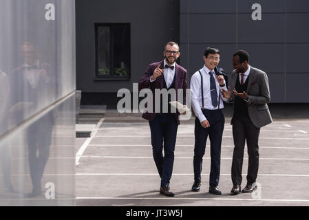 Lächelnd multikulturellen Team zu Fuß auf der Straße in der Nähe von modernes Bürogebäude Stockfoto