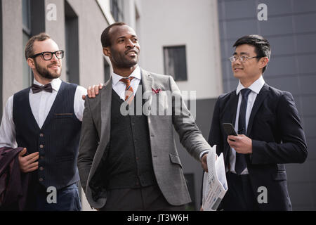 Junge stilvolle multiethnischen Geschäftsleute in formale Walking im Freien, Business Team Meeting Stockfoto