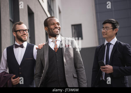 Junge stilvolle multiethnischen Geschäftsleute in formale Walking im Freien, Business Team Meeting Stockfoto