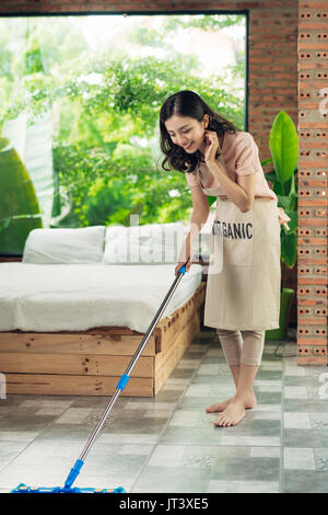 Hausarbeit und Hauswirtschaft Konzept. Frau, die Reinigung des Bodens mit Mop im Innenbereich Stockfoto