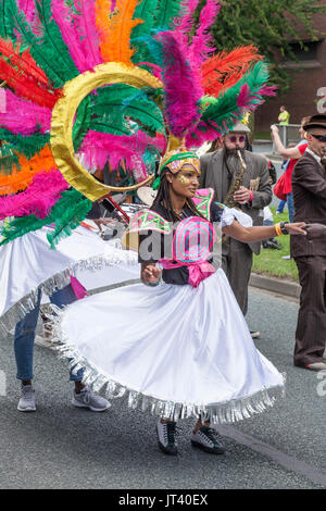 Eine junge schwarze Frau in bunten Kopf Kleid Tänze entlang der Straße an der Stockton Internationale Riverside Festival Parade Stockfoto