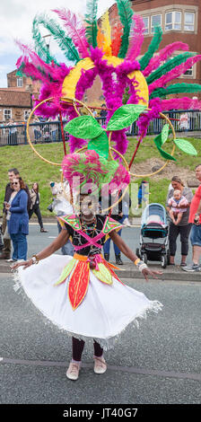 Eine junge schwarze Frau in bunten Kopf Kleid Tänze entlang der Straße an der Stockton Internationale Riverside Festival Parade Stockfoto