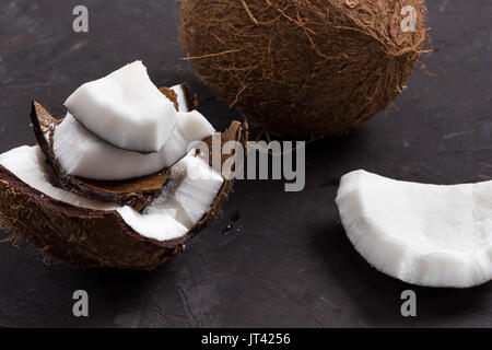 Nahaufnahme der Stücke von reifen tropischen Kokos auf dunklem Hintergrund Stockfoto