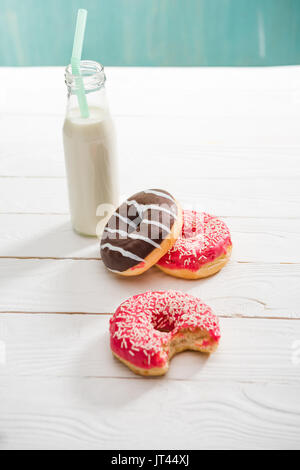 Hohe Betrachtungswinkel von milchshake in Glasflasche mit süßen Krapfen auf dem Tisch Stockfoto