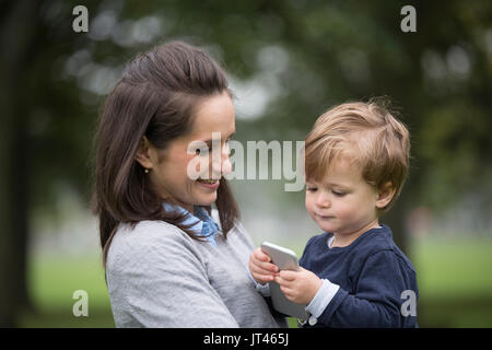 Junge Junge spielt mit seinen Müttern smart phone. Stockfoto