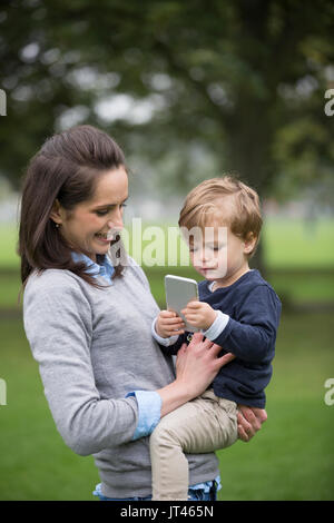 Junge Junge spielt mit seinen Müttern smart phone. Stockfoto