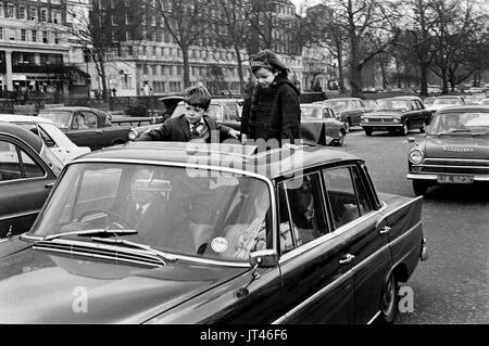 Britische Kinder aus den 1970er Jahren stehen auf Autositzen und stehen durch das Schiebedach, während das Auto im Londoner Verkehr gefahren wird. Park Lane, London England 1970 HOMER SYKES Stockfoto