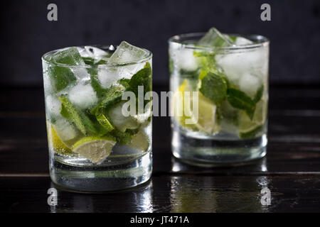 Nahaufnahme der Mojito Cocktail in Gläsern auf dunklen Holztisch, cocktail Getränke Konzept Stockfoto
