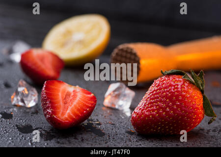 Holz- saftpresse mit Zitrone und Erdbeeren Schichten auf Stein, Barkeeper cocktail Stockfoto