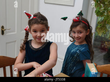 Schwestern an Weihnachten mit festlichen Alice Bands in ihrem Haar, Surrey, England Stockfoto