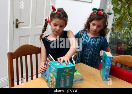 Schwestern an Weihnachten mit festlichen Alice Bands in ihren Haaren auf Sammlung von Enid Blyton Bücher das Naughtiest Girl Surrey, England Stockfoto