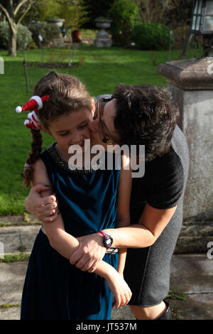 Mutter umarmen und küssen Auf Wange Tochter im Garten, Surrey, England Stockfoto