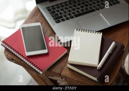 Pen, Notebooks, Smartphones und Laptops auf kleinen hölzernen Tisch. zu Hause arbeiten am Wochenende Konzept Stockfoto