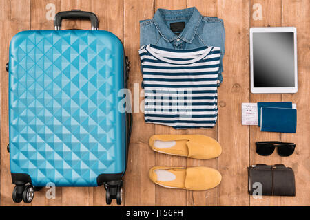 Flach mit Gepäck, männliche Kleidung, Zubehör und digitalen Tablette auf Holzboden. Bereit für Travel Concept Stockfoto