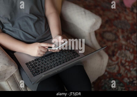 Frau freier Mitarbeiter mit Smartphone für soziales Netzwerk während der Arbeit mit dem Laptop. on-line-Geschäft und Self-concept beschäftigt Stockfoto