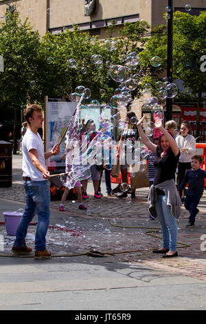 Street Performer Erstellen großer Seifenblasen bubble Zauberstab Unterhaltung der Massen in Dundee, Großbritannien Stockfoto